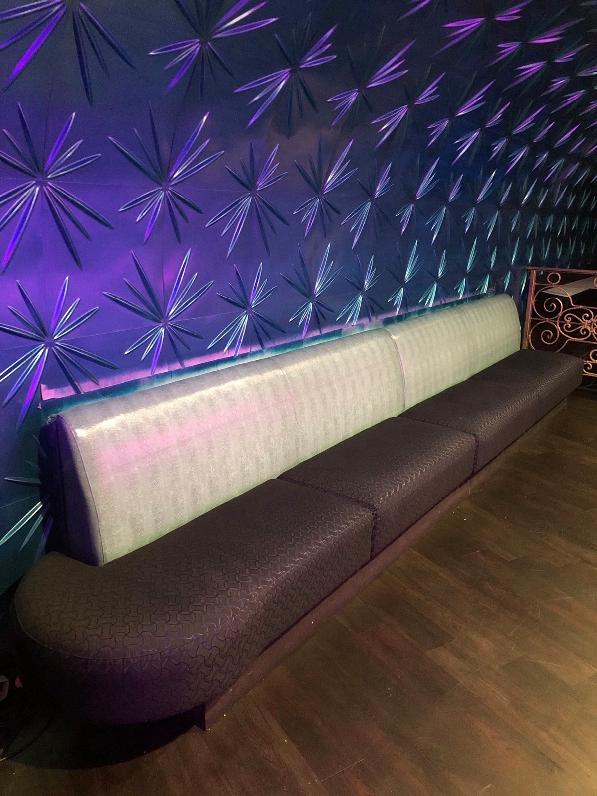 Booth seating in a lounge with a purple-lit starburst accent wall panel
