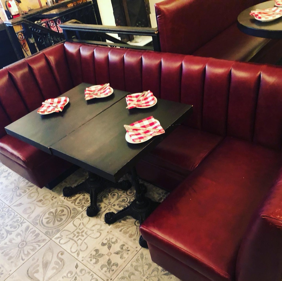 Deep burgundy vinyl booth seating in an Italian bistro with patterned floor tile