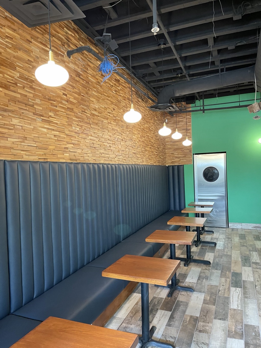 Navy channel-tufted banquette along a reclaimed wood wall with pendant lighting