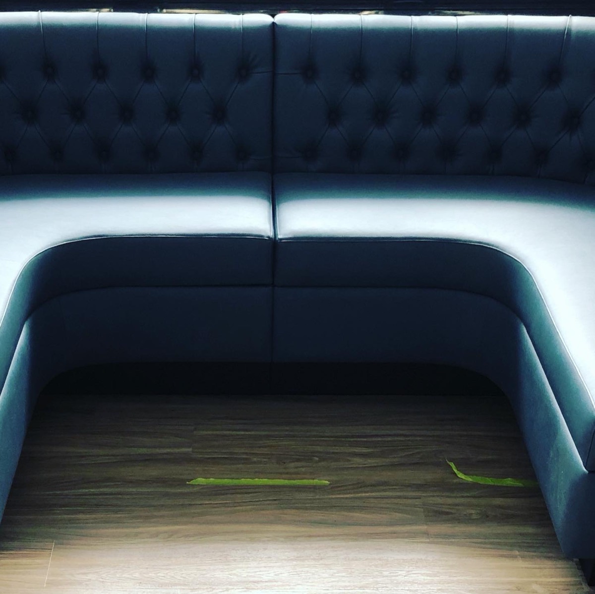 Dark navy channel-tufted curved booth seating under dim mood lighting