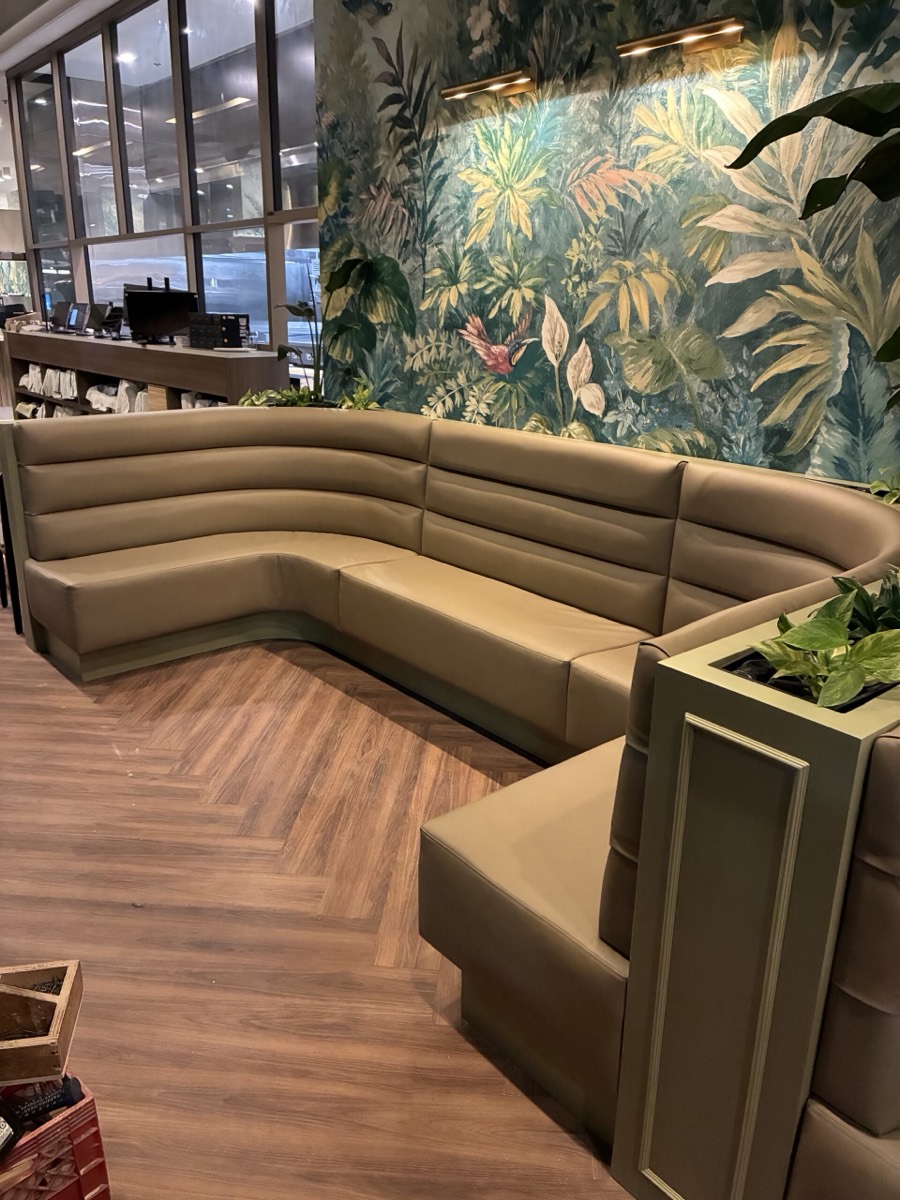 Curved olive banquette seating in front of a botanical hummingbird mural